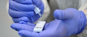 Ein Helfer verarbeitet eine Probe für einen Corona-Schnelltest.