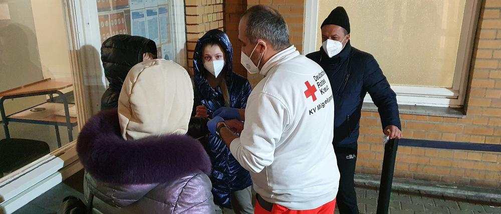 Geflüchtete aus der Ukraine nach der Ankunft in Berlin mit Rot-Kreuz-Helfer.