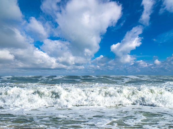 Strand Costa de la Luz mit Wolken und Brandungswellen, Spanien.