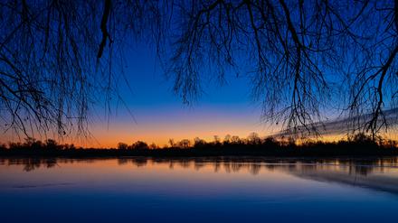 Kurz vor Sonnenaufgang leuchtet der Morgenhimmel farbenprächtig über dem deutsch-polnischen Grenzfluss Oder.