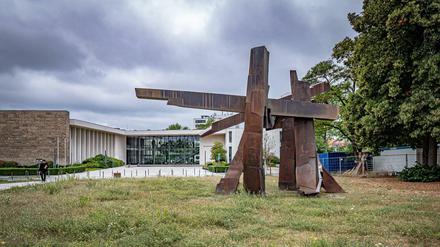 Aus einer ungemähten Wiese steht eine abstrakte Skulptur.