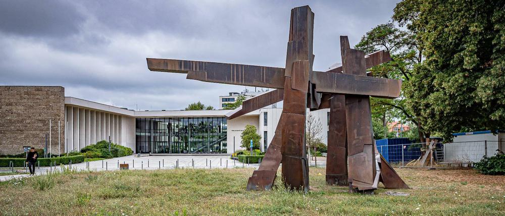Aus einer ungemähten Wiese steht eine abstrakte Skulptur.