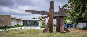 Aus einer ungemähten Wiese steht eine abstrakte Skulptur.