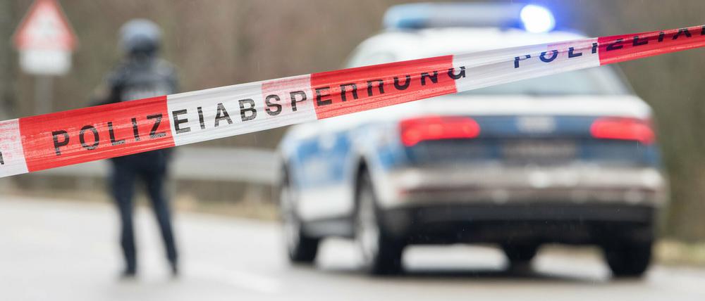 Polizeibeamte stehen an einer Absperrung an der Kreisstraße 22, rund einen Kilometer von dem Tatort entfernt, an dem zwei Polizeibeamte durch Schüsse getötet wurden.