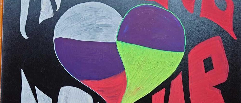 Tafel mit Spruch "Make Love not war" sowie russsischer und ukrainischer Flagge als Herz am russischen Restaurant "Datscha" in Berlin-Kreuzberg.