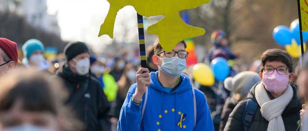 Ein junger Demonstrant in Hamburg trägt die Papp-Silhouette der Ukraine in den Landesfarben mit einem Peace-Zeichen.