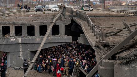Ukrainer drängen sich unter einer zerstörten Brücke in Kiew