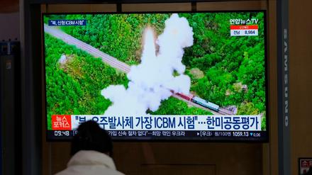 Eine Frau betrachtet einen Fernsehbildschirm in einem Bahnhof, auf dem eine Nachrichtensendung über Nordkoreas Raketen gezeigt wird.