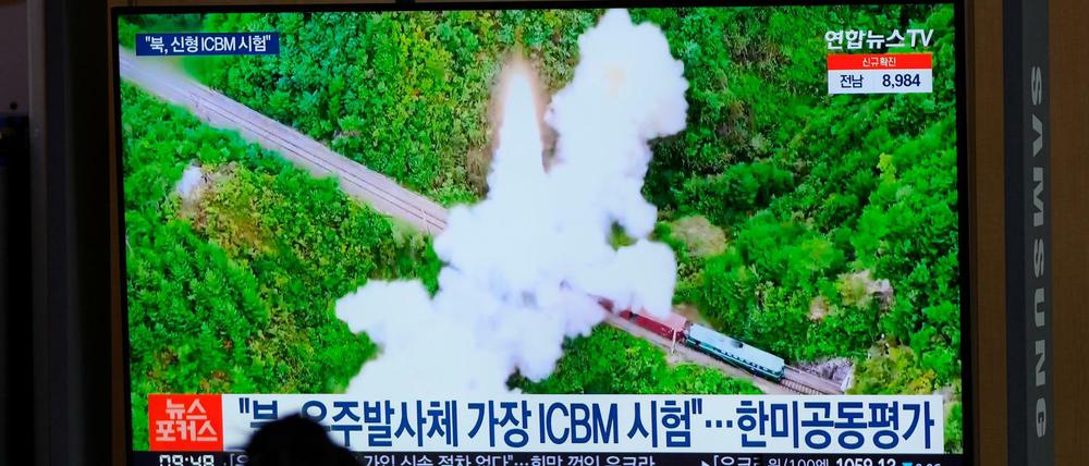 Eine Frau betrachtet einen Fernsehbildschirm in einem Bahnhof, auf dem eine Nachrichtensendung über Nordkoreas Raketen gezeigt wird.