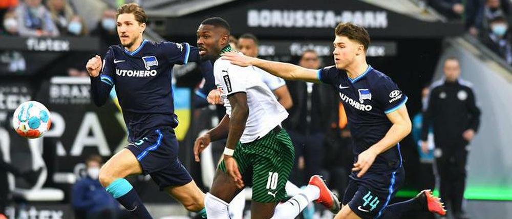 Gladbachs Marcus Thuram auf dem Weg, begleitet von Niklas Stark und Linus Gechter (r.)