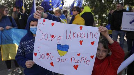 Kinder halten bei einer Demonstration für den Frieden ein Plakat mit der Aufschrift „Rettet die Ukraine, rettet unsere Menschen“.