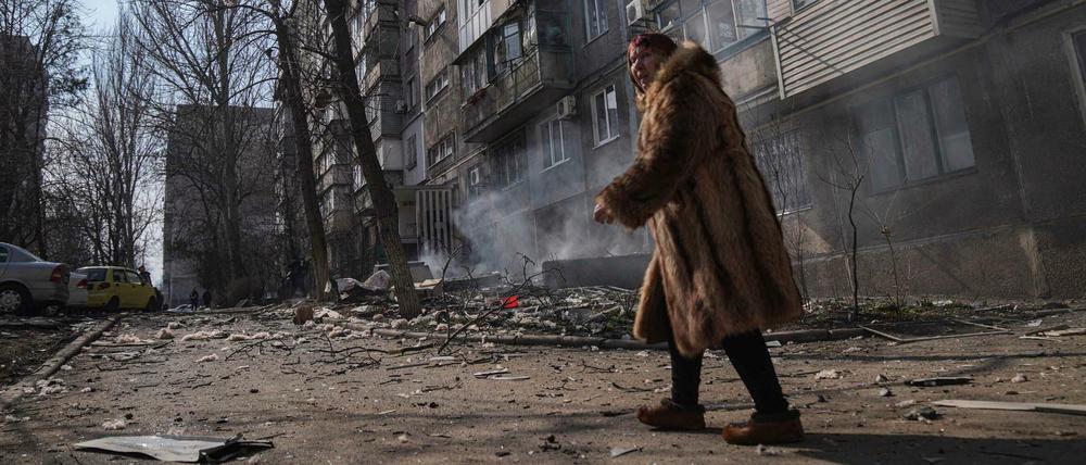 Eine Frau vor einem brennenden Wohnhaus in Mariupol