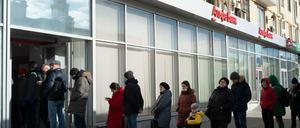 Menschen stehen in einer Schlange, um Geld von einem Geldautomaten der Alfa Bank in Moskau abzuheben.
