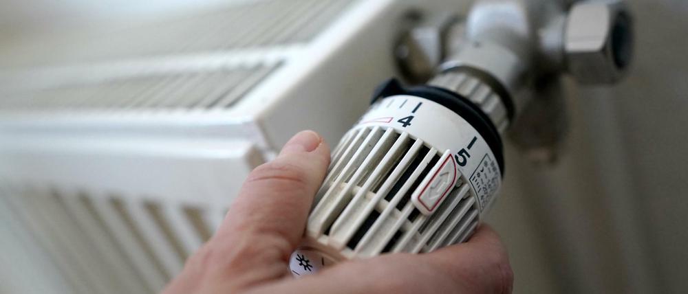 Eine Frau dreht an einem Heizungsthermostat.