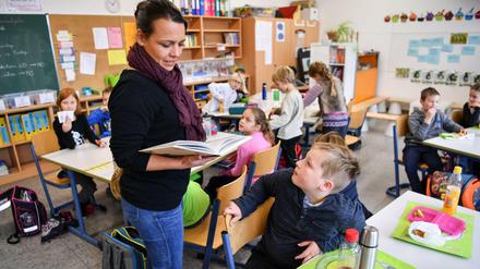 Eine Lehrerin liest ihren Drittklässlern aus einem Buch vor.