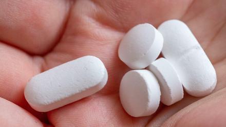 Eine Person hält Tabletten und Vitaminpräparate von Calcium, Vitamin D und Magnesium in der Hand