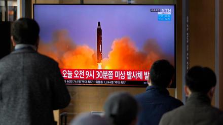 Menschen schauen auf einen Fernsehbildschirm, auf dem eine Nachrichtensendung mit Filmmaterial über Nordkoreas Rakete gezeigt wird, in einem Bahnhof in Seoul.