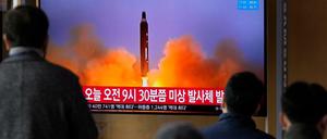 Menschen schauen auf einen Fernsehbildschirm, auf dem eine Nachrichtensendung mit Filmmaterial über Nordkoreas Rakete gezeigt wird, in einem Bahnhof in Seoul.