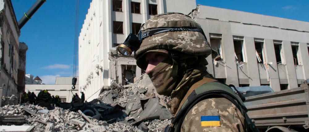 Ein ukrainischer Soldat bewacht ein durch Beschuss beschädigtes Gebäude in Charkiw. 