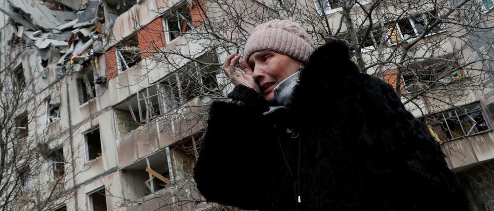 Eine Frau vor einem zerstörten Haus in Mariupol