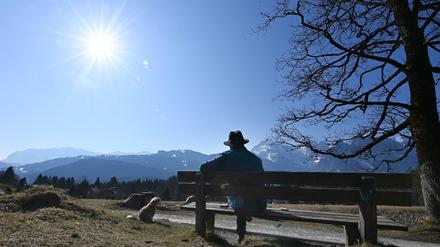 Eine Person gönnt sich in Garmisch-Partenkirchen eine Ruhepause auf einer Bank. 