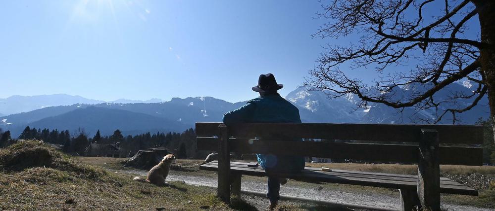 Eine Person gönnt sich in Garmisch-Partenkirchen eine Ruhepause auf einer Bank.
