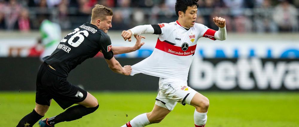 Augsburgs Frederik Winther (li.) zerrt am Trikot von Stuttgarts Wataru Endo (re.). Den Heimsieg von Stuttgart kann er dann aber auch nicht verhindern.