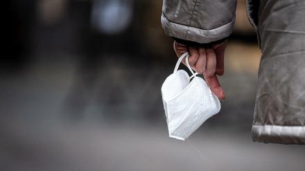 Eine Passantin hält eine FFP-2 Maske in der Hand. Sie muss derzeit nur in Kliniken, Pflegeheimen, Bussen und Bahnen getragen werden.