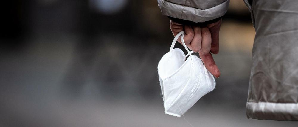 Eine Passantin hält eine FFP-2 Maske in der Hand. Sie muss derzeit nur in Kliniken, Pflegeheimen, Bussen und Bahnen getragen werden.