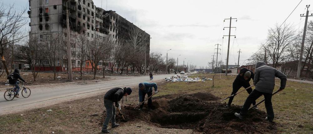 Einwohner von Mariupol schaufeln ein Grab. 