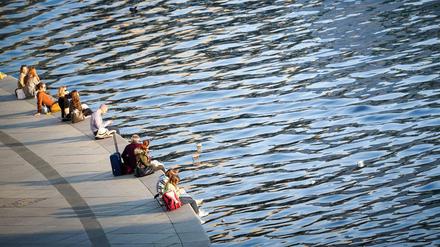 Einfach mal die Beine baumeln lassen: Menschen genießen den Sonnenschein am Ufer der Spree im Berliner Regierungsviertel.