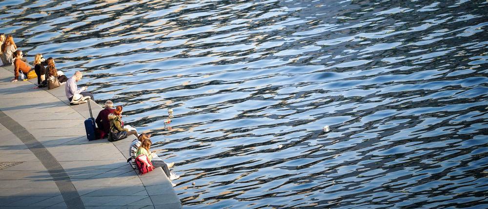 Einfach mal die Beine baumeln lassen: Menschen genießen den Sonnenschein am Ufer der Spree im Berliner Regierungsviertel.