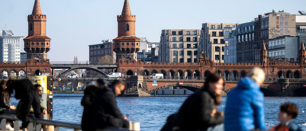 Zahlreiche Menschen genießen das sonnige Wetter am Spreeufer vor der Kulisse der Oberbaumbrücke.