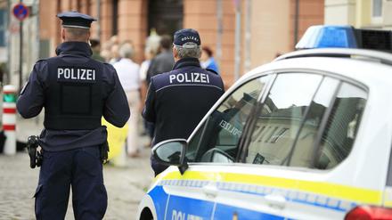 Polizisten vor einem Streifenwagen (Symbolbild)