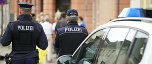Polizisten vor einem Streifenwagen (Symbolbild)