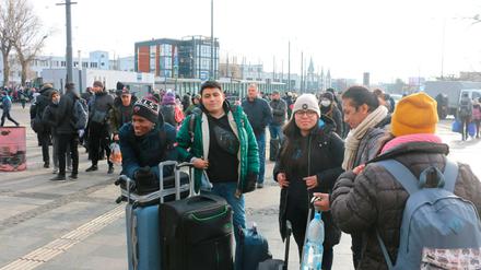 Fünf junge Männer und Frauen stehen mit ihren Koffern vor einem Bahnhofsgebäude.