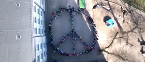 Schüler:innen formieren sich zu Peace-Zeichen, Screenshot aus einem aus der Luft gefilmten Video.