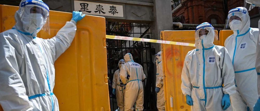 Mit einer Plastikmauer riegeln Mitarbeiter der Gesundheitsbehörden einen Wohnkomplex in Shanghai ab.