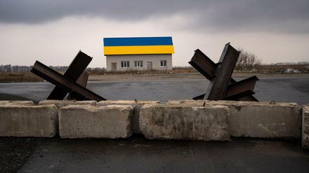 Panzersperren bei einem Haus in den Farben der ukrainischen Flagge nahe Kiew