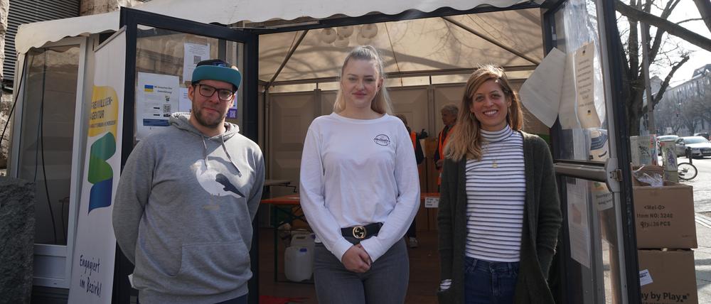 Helfer:innen Paul Müßig, Laura Stokar von Neuforn und Mareike Corrigan in einem Zelt vorm Rathaus Charlottenburg.