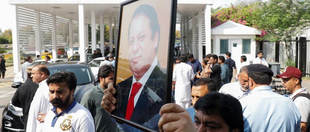 Ein pakistanischer Abgeordneter hält vor dem Misstrauensvotum ein Bild des Premier Khan in die Luft. 