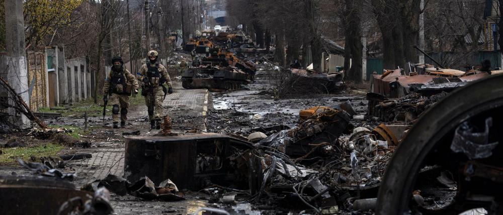 Zwei ukrainische Soldaten gehen durch die zerstörte Stadt Butscha.