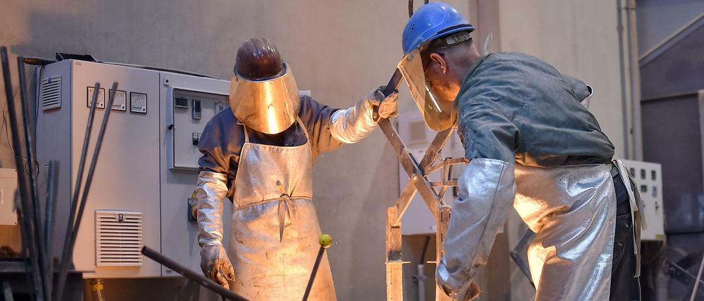 Arbeiter stehen in der Bildgießerei Noack in Berlin und holen geschmolzenes Metall aus einem Ofen. (Archivbild)