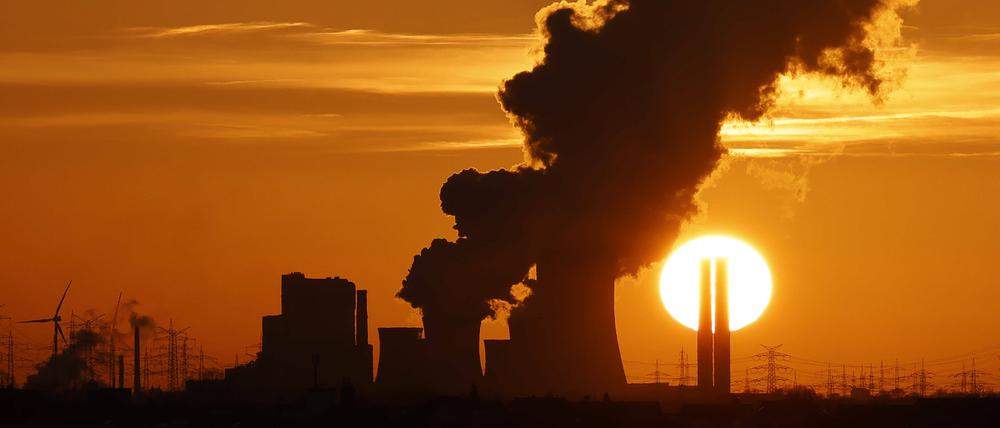 Das Kohlekraftwerk Niederaußem in Nordrhein-Westfalen zeichnet sich gegen die untergehende Sonne ab.
