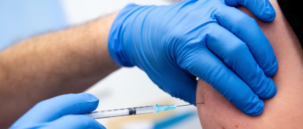 Ein Mann wird von einem Klinikmitarbeiter mit dem Corona-Impfstoff von Biontech/Pfizer geimpft. 