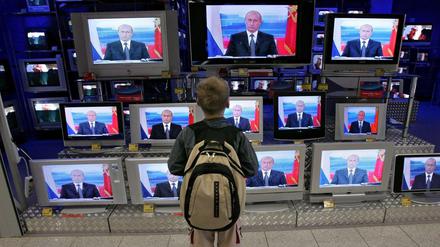 Ein Kind schaut sich Putin im Fernsehen an.
