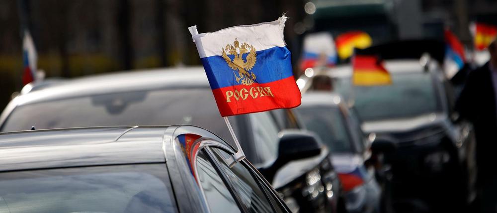 Flaggen mit den russischen Nationalfarben wehen an einem Auto auf dem Olympiaplatz in Berlin.