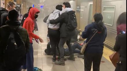 Menschen helfen weiteren verletzten Personen an einer U-Bahn-Station im New Yorker Stadtteil Brooklyn.