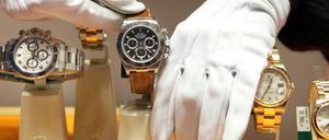 Mit weißen Handschuhen werden Luxusuhren der elitären Schweizer Uhrenmanufaktur Rolex in einem Schaufenster platziert