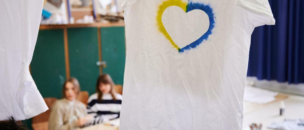 Ein T-Shirt mit einem Herz, umrahmt von den ukrainischen Farben hängt im Klassenraum einer Willkommensklasse am Willy-Graf-Gymnasium in Berlin-Lichterfelde.